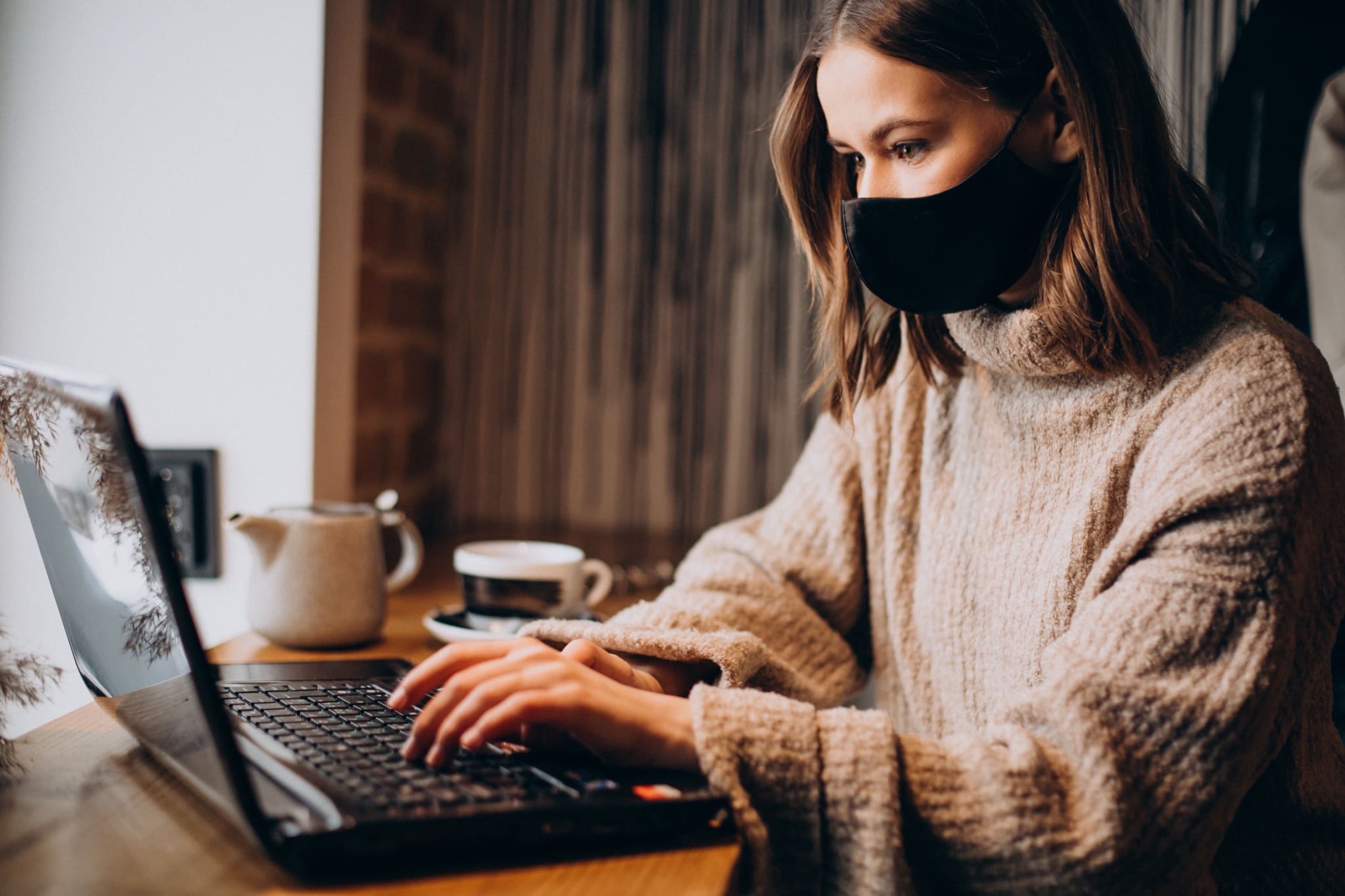 young woman working laptop cafe wearing mask copy - Distanțarea socială și efectele psihologice asupra comportamentelor de consum în real estate